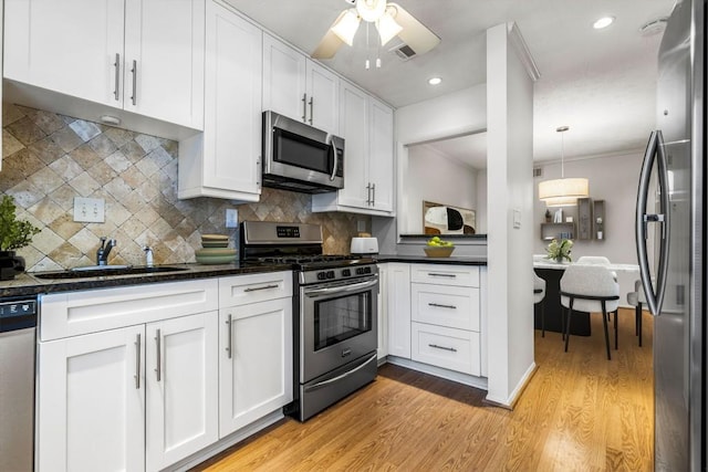 kitchen featuring sink, light hardwood / wood-style flooring, stainless steel appliances, white cabinets, and decorative light fixtures