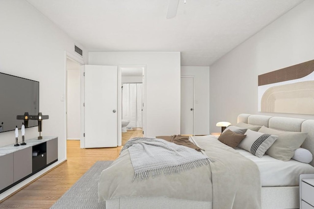 bedroom featuring ceiling fan, ensuite bathroom, and light wood-type flooring