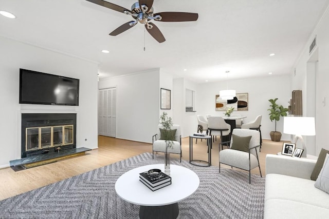 living room with ceiling fan, crown molding, and light hardwood / wood-style floors