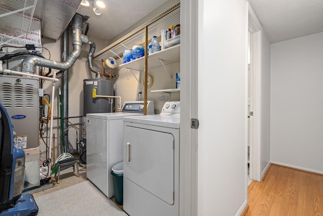 washroom with light hardwood / wood-style floors, washing machine and dryer, and water heater