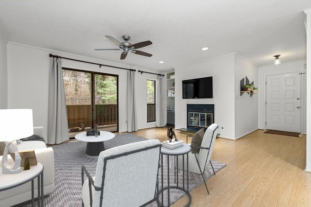 living room featuring ornamental molding, light hardwood / wood-style floors, and ceiling fan