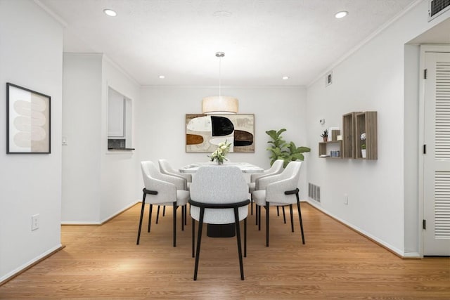 dining area with crown molding and light hardwood / wood-style flooring