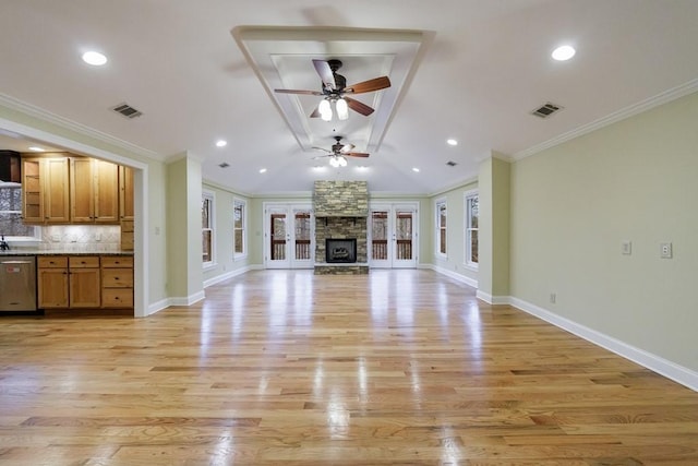 unfurnished living room featuring french doors, light hardwood / wood-style flooring, crown molding, and a stone fireplace