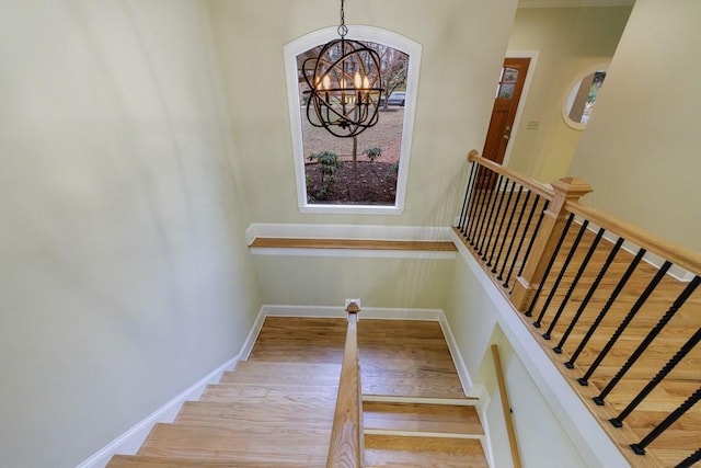 stairs featuring a notable chandelier and wood-type flooring