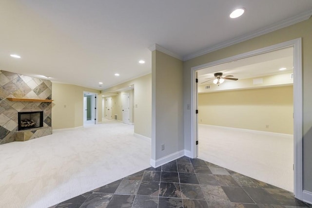 unfurnished living room with ceiling fan, a tile fireplace, dark carpet, and ornamental molding