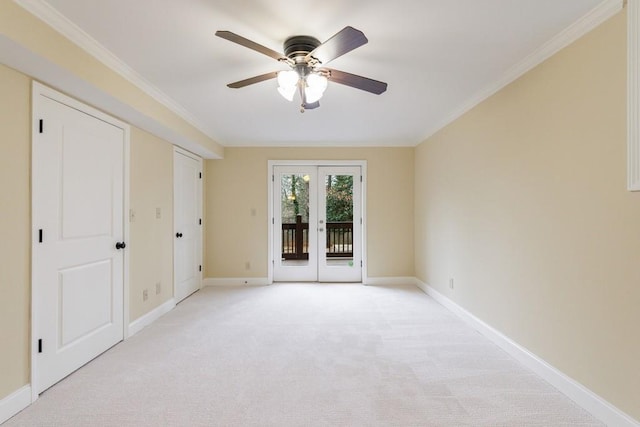 carpeted spare room with ornamental molding, ceiling fan, and french doors