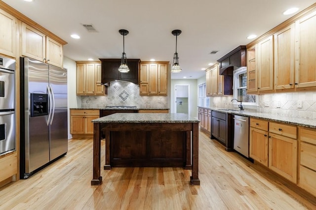 kitchen with a center island, light hardwood / wood-style floors, pendant lighting, stainless steel appliances, and light stone counters