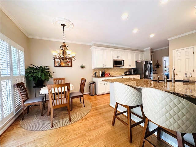1739 Praters Pt, Dacula, GA 30019 - kitchen featuring appliances with stainless steel finishes, a chandelier, light wood-style flooring, crown molding, and white cabinetry