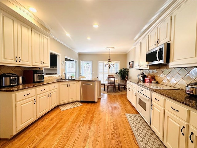 1739 Praters Pt, Dacula, GA 30019 - kitchen featuring appliances with stainless steel finishes, a sink, a peninsula, light wood-style floors, and ornamental molding