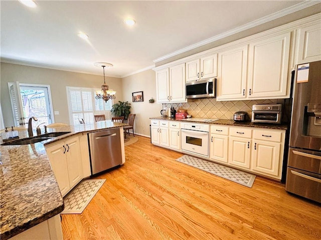 1739 Praters Pt, Dacula, GA 30019 - kitchen with stainless steel appliances, a sink, a chandelier, light wood-style floors, and decorative backsplash