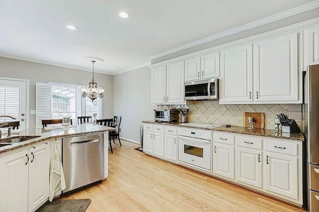 1739 Praters Pt, Dacula, GA 30019 - kitchen featuring appliances with stainless steel finishes, a sink, white cabinetry, crown molding, and backsplash