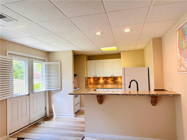 1739 Praters Pt, Dacula, GA 30019 - kitchen with freestanding refrigerator, a kitchen breakfast bar, light stone countertops, a peninsula, and recessed lighting