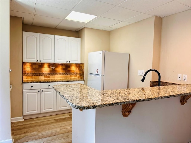 1739 Praters Pt, Dacula, GA 30019 - kitchen with freestanding refrigerator, dark stone counters, a kitchen breakfast bar, a peninsula, and white cabinetry