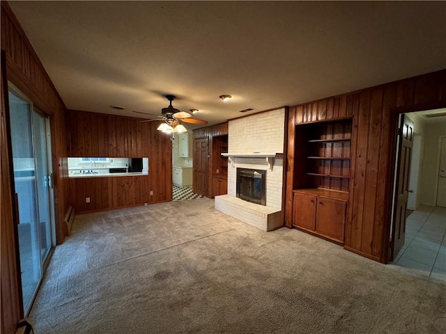 unfurnished living room featuring ceiling fan, wood walls, light carpet, and a fireplace