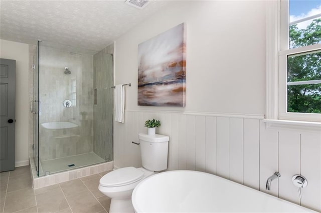 2015 Clipper Straits, Snellville, GA 30078 - bathroom with tile patterned flooring, a freestanding tub, a stall shower, a textured ceiling, and a wainscoted wall