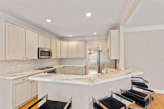 kitchen with a kitchen breakfast bar, tasteful backsplash, appliances with stainless steel finishes, and a peninsula