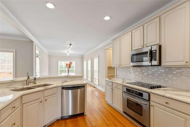 kitchen with a sink, cream cabinetry, appliances with stainless steel finishes, and crown molding