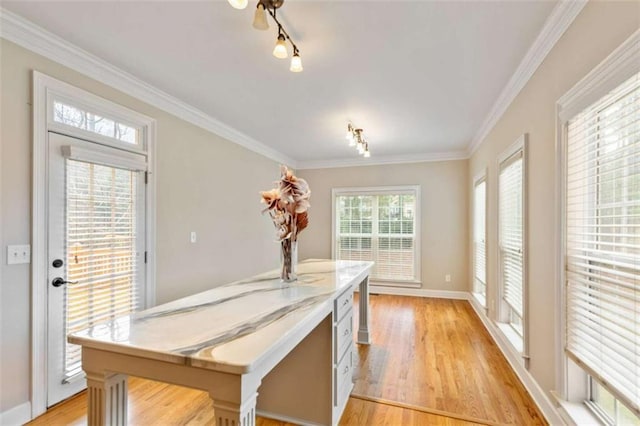 dining area with crown molding, baseboards, light wood finished floors, and track lighting