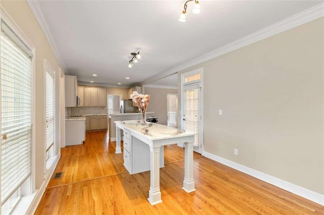 kitchen featuring light wood-style flooring, an island with sink, freestanding refrigerator, ornamental molding, and light countertops