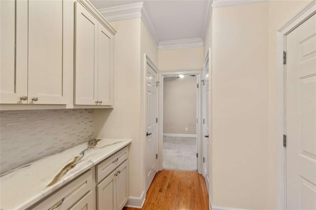 interior space featuring light wood-style flooring, baseboards, backsplash, and ornamental molding