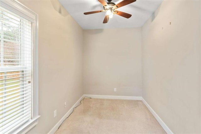 empty room with a healthy amount of sunlight, light colored carpet, baseboards, and ceiling fan