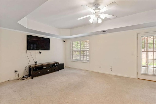 living area with a raised ceiling, a ceiling fan, visible vents, and light carpet