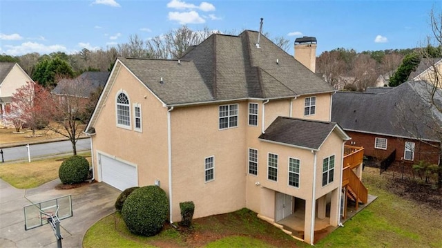 back of house with an attached garage, a chimney, a yard, and concrete driveway