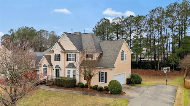 view of front of property with a shingled roof, a front lawn, stucco siding, driveway, and an attached garage