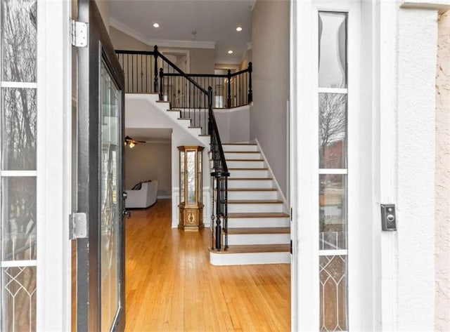 entryway with stairway, ornamental molding, recessed lighting, a high ceiling, and wood finished floors