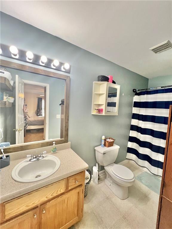 full bathroom featuring visible vents, toilet, vaulted ceiling, vanity, and a shower with curtain