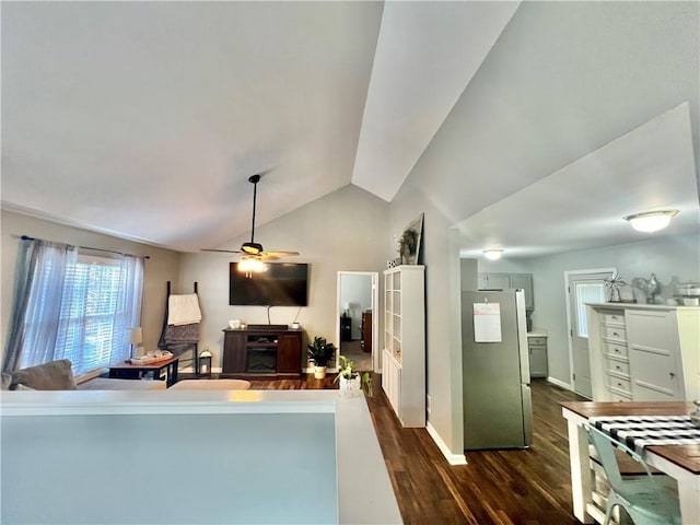 living area featuring dark wood-style floors, ceiling fan, baseboards, and vaulted ceiling