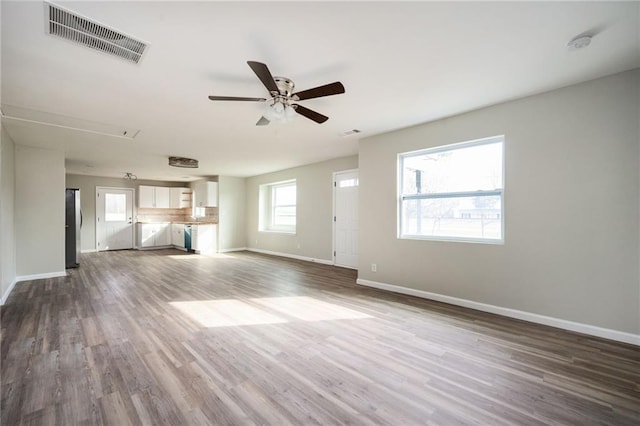 unfurnished living room featuring dark wood finished floors, visible vents, baseboards, and ceiling fan