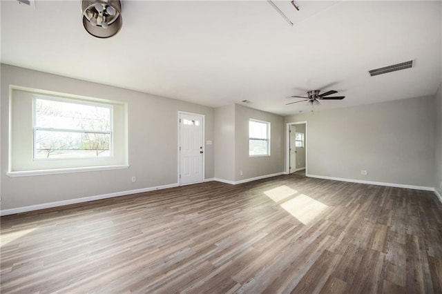 unfurnished living room with visible vents, a ceiling fan, baseboards, and wood finished floors