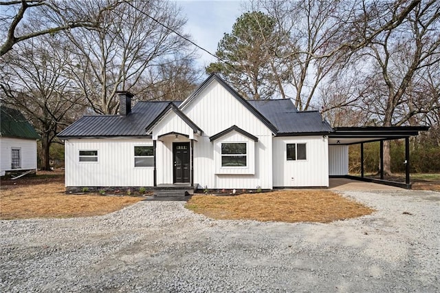 modern farmhouse style home featuring metal roof, a carport, gravel driveway, and a chimney