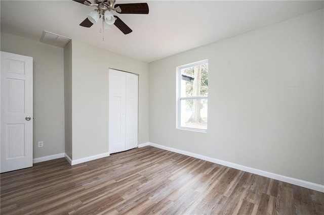 unfurnished bedroom featuring wood finished floors, baseboards, a closet, and ceiling fan