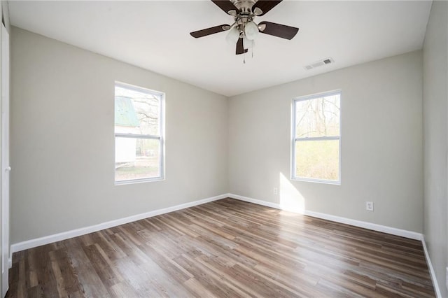 spare room featuring ceiling fan, visible vents, baseboards, and wood finished floors