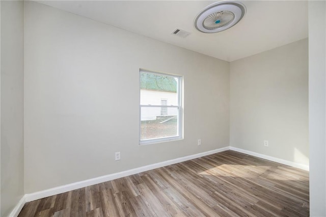 empty room featuring visible vents, wood finished floors, and baseboards