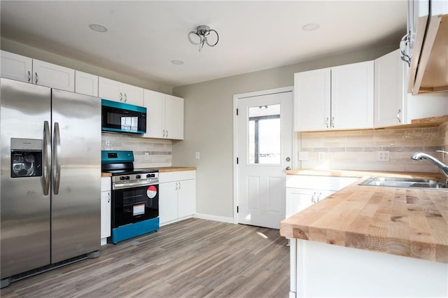 kitchen featuring a sink, stainless steel appliances, white cabinets, light wood-style floors, and butcher block counters