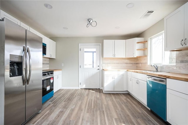 kitchen with dishwashing machine, visible vents, light wood-style flooring, stainless steel fridge with ice dispenser, and range