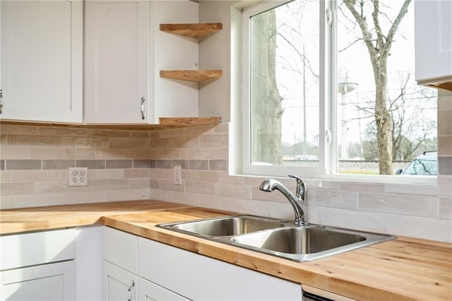 kitchen with plenty of natural light, open shelves, wood counters, and a sink