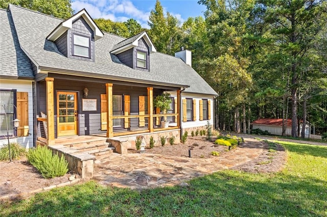 view of front of property with a porch, a chimney, and roof with shingles