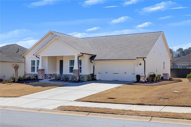 view of front of house featuring driveway, central AC unit, stone siding, an attached garage, and a front yard