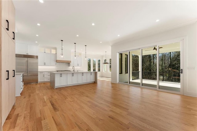 kitchen with built in fridge, light wood finished floors, tasteful backsplash, open floor plan, and white cabinetry