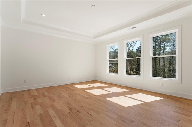 unfurnished room featuring recessed lighting, baseboards, light wood-style floors, ornamental molding, and a tray ceiling