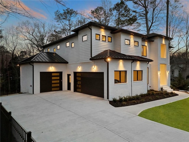 modern home with metal roof, driveway, brick siding, and a standing seam roof