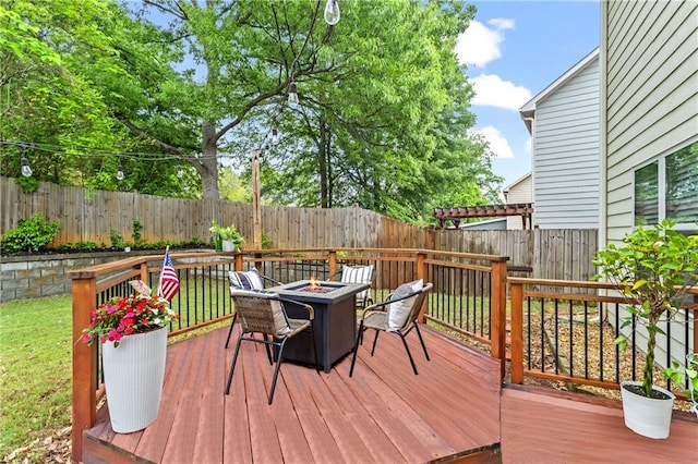 wooden terrace with a fire pit and a fenced backyard