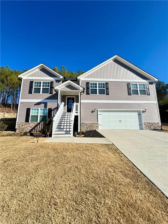 view of front of house with a garage, concrete driveway, board and batten siding, and stone siding