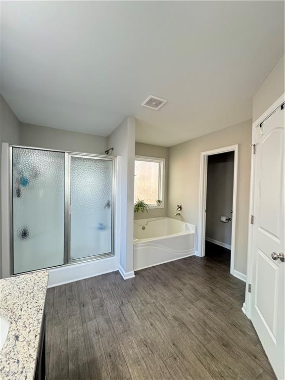 bathroom featuring a bath, a stall shower, wood finished floors, and visible vents