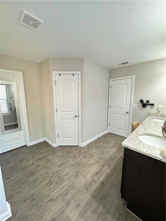 bathroom featuring visible vents, a sink, baseboards, and wood finished floors