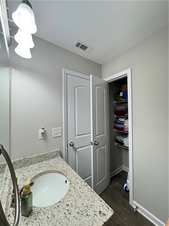 bathroom with vanity, wood finished floors, visible vents, and baseboards